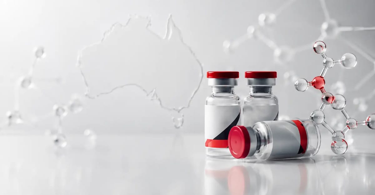 Three vaccine vials with red lids on a reflective surface, one lying down, beside a molecular model and Australia outline in back.